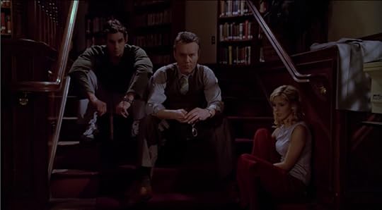 Buffy, Giles, and Xander sit on the steps in the library, in the dark, all with shocked/numb expressions.