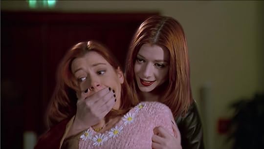 Willow, wearing a pink sweater with daisies on it because she's goddamn adorable, is standing in front of Vampire!Willow, who has her hand over Willow's mouth, restraining her. For reference, though not much of the outfit is seen in the picture, Vampire!Willow is decked out in a black leather corset shirt thing and matching black leather pants. Her skin is paler and she's wearing dramatic dark makeup.