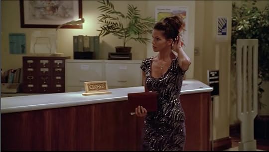 Cordelia is wearing a black dress with a pattern of silver sequins on it. Her hair is pulled up. She's carrying a single book and not looking all that interested in it.