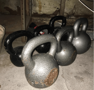 row of kettlebells in a garage gym