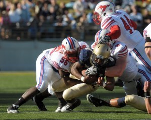101016-N-7647G-111 ANNAPOLIS, Md. (Oct. 16, 2010) U.S. Naval Academy quarterback Ricky Dobbs (#4) is tackled by Southern Methodist University linebacker Ja'Gared Davis (#56), defensive end Taylor Thompson (#8), and line backer Taylor Reed (#44) during the first quarter of a college football game at the U.S. Naval Academy. The Midshipmen won the game 28-21. (U.S. Navy photo by Mass Communication Specialist 2nd Class Jason M. Graham/Released)