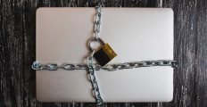 Heavy with a padlock around a laptop isolated on grey table.