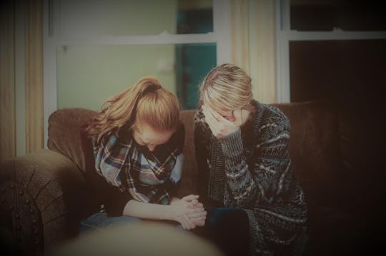 two women sitting on a sofa and praying together
