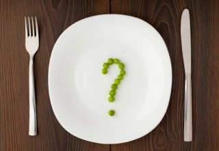 Question mark made of peas on a white plate
