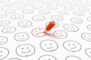 A lot of gray happy smileys and one red unhappy smiley drawn by red pencil. Bad mood and unhappiness concept