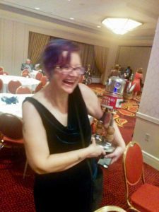 Picture of SFWA President Cat Rambo holding a small robot sculpture