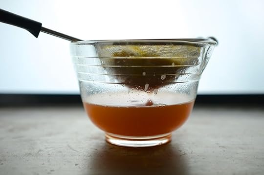 Side view of straining honey sweetened rhubarb meyer lemon cordial.