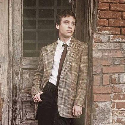 Image may contain: 1 person, standing and suit