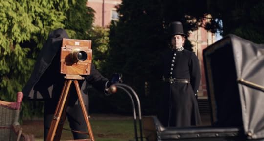 A Victorian camera is set up to take a photograph of a pram. A Victorian policeman looks on.