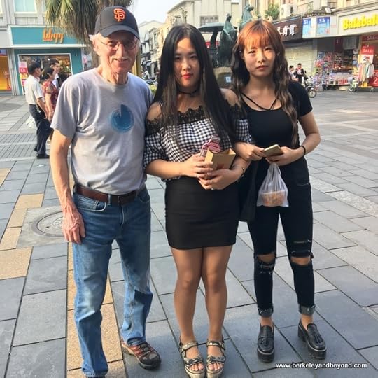 teen girls pose with American on Five Horses Pedestrian Shopping Area in Wenzhou, China