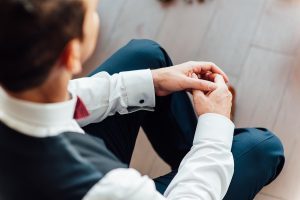Man Sits With Hands Clasped