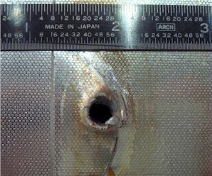 Image of the entry hole created on Space Shuttle Endeavour's radiator panel by the impact of unknown space debris.
