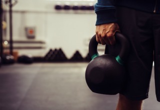 Close-up of man holding heavy kettlebell at gym