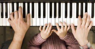 woman and child's hands on piano keys