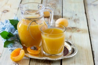 The refreshing summer drink with peach in a jug and glasses on a wooden table