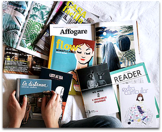 A pair of hands holding one magazine against a large pile.