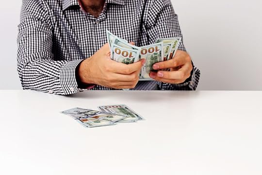 man counts $100 bills and leaves some on table