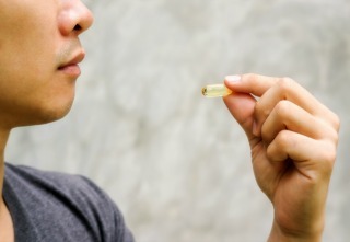 Close up of a man take a fish oil capsule.