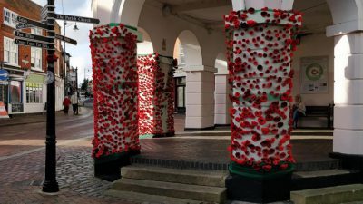 red knitted poppies cover white pillars of a grand portico