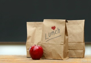 Paper lunch bags with red apple on school desk