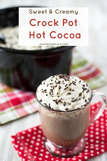 Coffee mug filled with Crock Pot Hot Cocoa topped with whipped cream and brown sprinkles.
