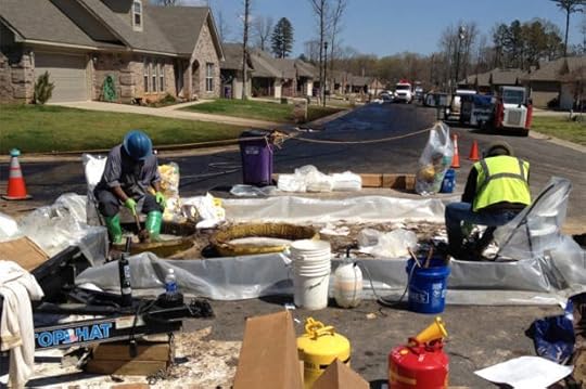 Workers scrub crude oil from their boots in the Northwoods subdivision where an ExxonMobil pipeline ruptured in Mayflower