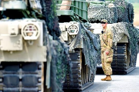 An US soldier waits in front of a tank type 'M1A2 SEP'