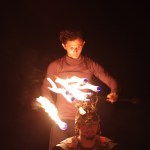 Man lighting torches on another's head in the dark