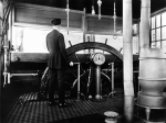 Pilot Harry English at the wheel in the pilothouse of the Str. Queen City, 1918