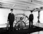 Captain Ben Pattison and Pilot Harry W. Doss stand beside the wheel in the pilothouse of the Str. Island Queen