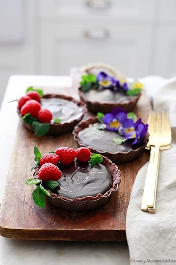 Beautiful no-bake chocolate almond butter tarts topped with raspberries and edible flowers.