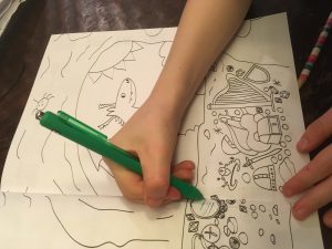 Rowan's dragon book with his hand over paper