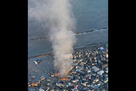 Fire smokes billow from residences as a coastal area is flooded by waters after a tsunami in Iwaki, Fukushima prefecture (state), Japan, Friday, March 11, 2011.