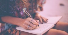 boho-girl-writing-in-her-diary-wearing-a-floral-dress-picture-id472391844