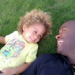real men: father lying on grass with toddler