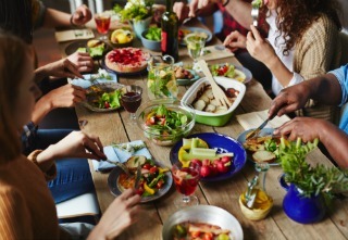 Hungry people eating appetizing vegetarian dinner