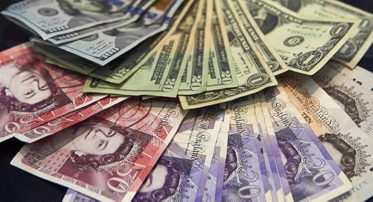 A cashier displays multiple denomination US dollar and British pound Sterling bank notes