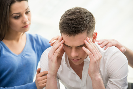 35457536 - feeling pain and depression. depressed young man is sitting at the chair while woman is comforting his.