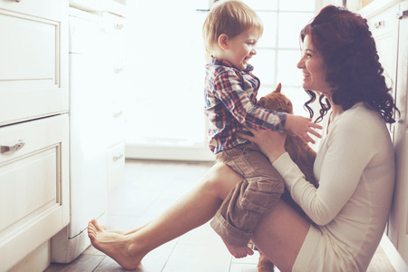 36331272 - mother with her baby playing with pet on the floor at the kitchen at home