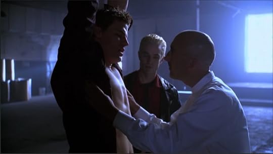 Angel is suspended by his arms and Marcus the torture guy has opened Angel's shirt while Spike looks on. Behind them is a gigantic window with sunlight streaming in.