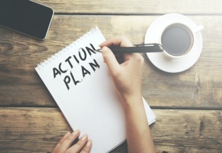 woman write action plan text on notebook with coffee and phone on table