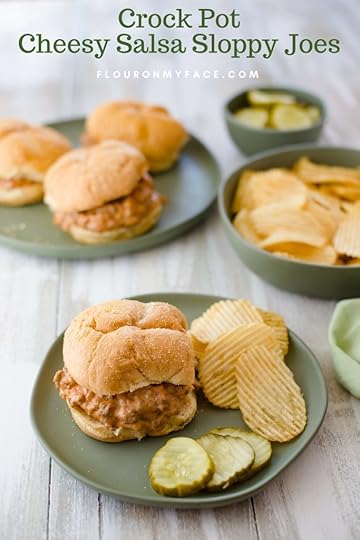 Crock Pot Cheesy Salsa Sloppy Joes served on a green plate with potato chips and pickle slices