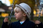 young boy on swing with hat on