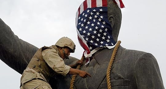 A US Marine covers the head of a statue of Iraqi President Saddam Hussein with the US flag before pulling it down in Baghdad's al-Fardous (paradise) square 09 April 2003 as the marines swept into the Iraqi capital and the Iraqi leader's regime collapsed.
