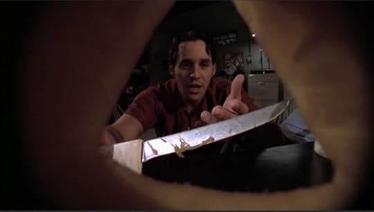 The camera is positioned inside a jack-o-lantern so that we're looking out through the nose to see Xander, holding a knife and staring at his pumpkin in confusion.