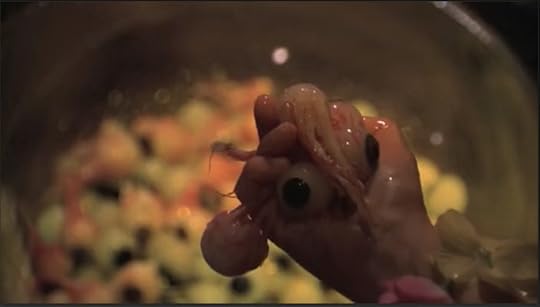 The girl's hand, full of actual eyeballs, above the bowl that is now full of eyeballs.