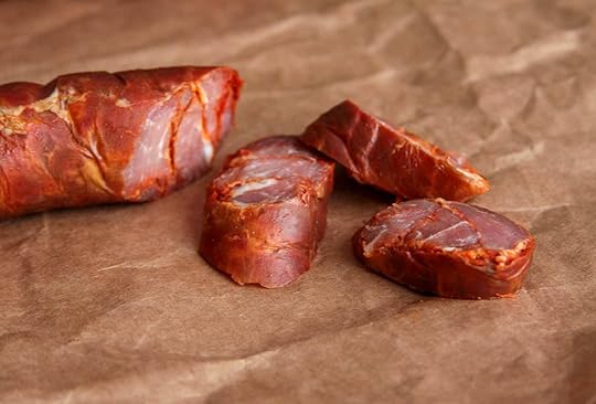 A link of Portuguese chouriço sausage with three slices on butcher paper