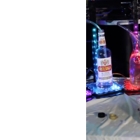 A selection of alcohol bottles with tubes deliver a mixed drink to a small cup.