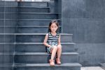 Asian girl sitting quietly on steps with striped dress on