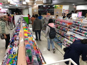 Photo of stationery store, three aisles of pens.